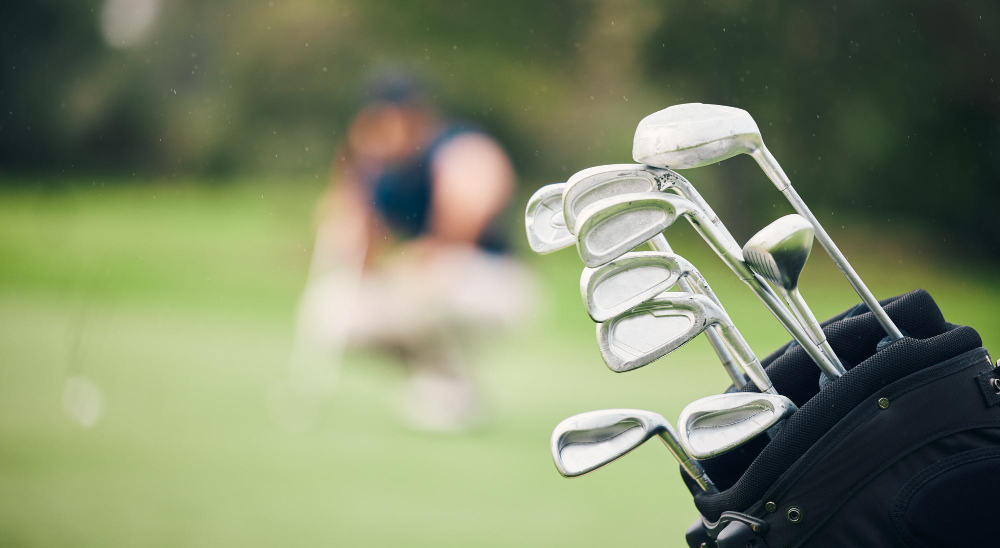 Golf clubs on focus with a golfer in the backround